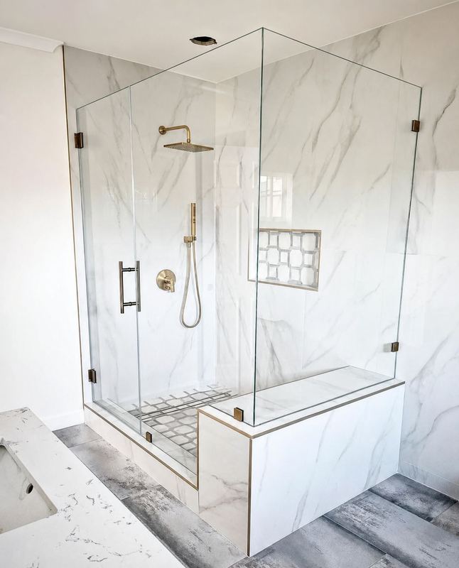 Frameless glass shower panels installed over a knee wall by Shower Enclosures by George